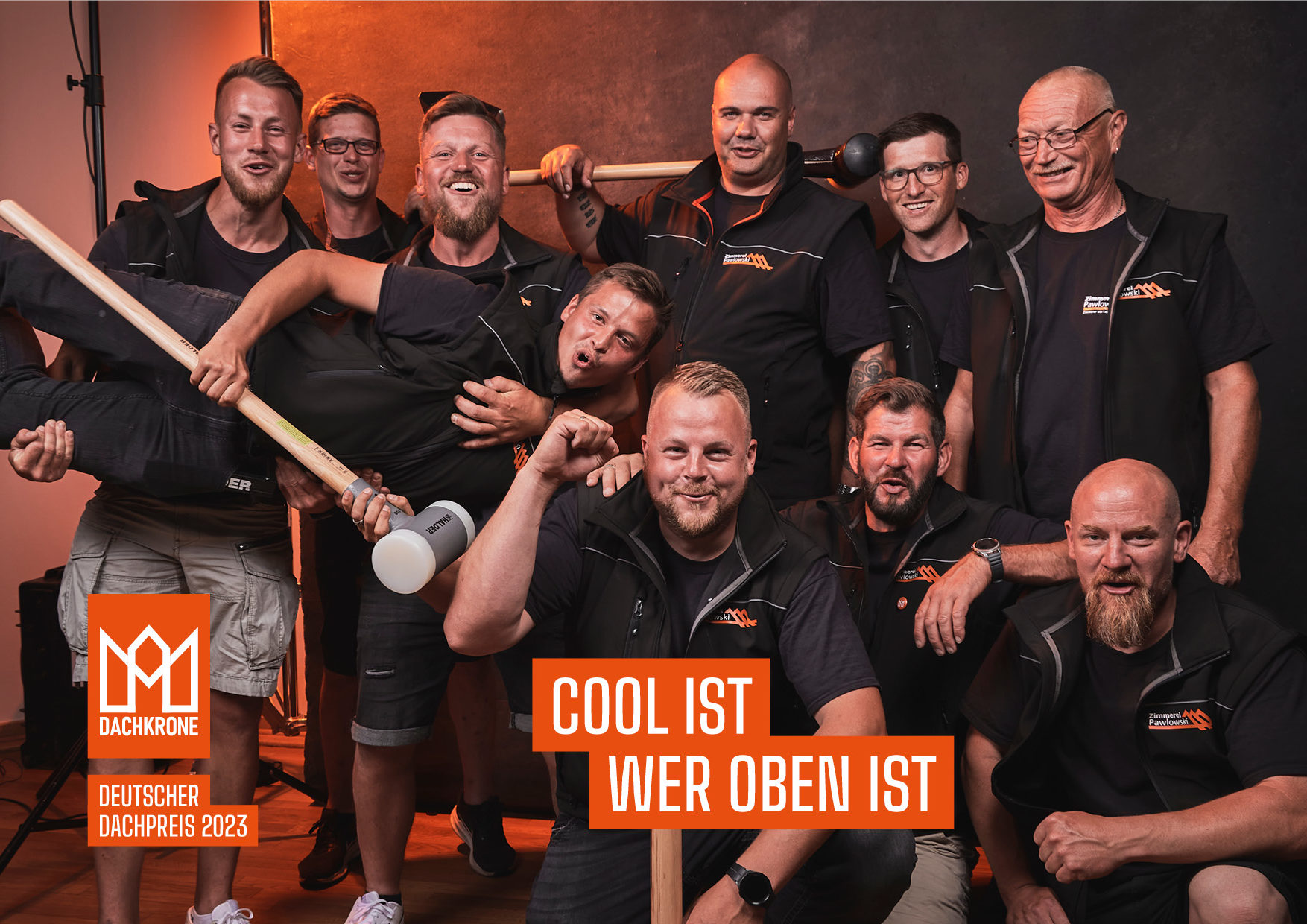 Das fröhliche Team der Zimmerei Pawlowski GmbH feiert den Deutschen Dachpreis 2023 mit einem humorvollen Gruppenfoto, das ihren starken Zusammenhalt zeigt.