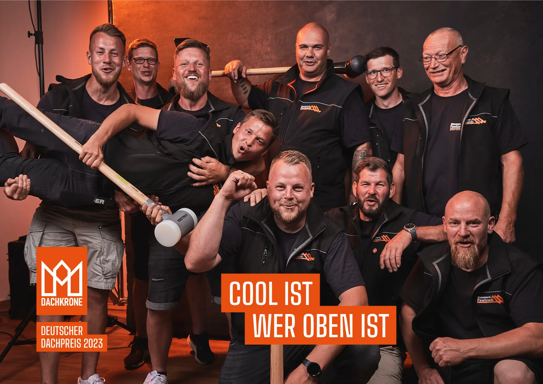 Das fröhliche Team der Zimmerei Pawlowski GmbH feiert den Deutschen Dachpreis 2023 mit einem humorvollen Gruppenfoto, das ihren starken Zusammenhalt zeigt.