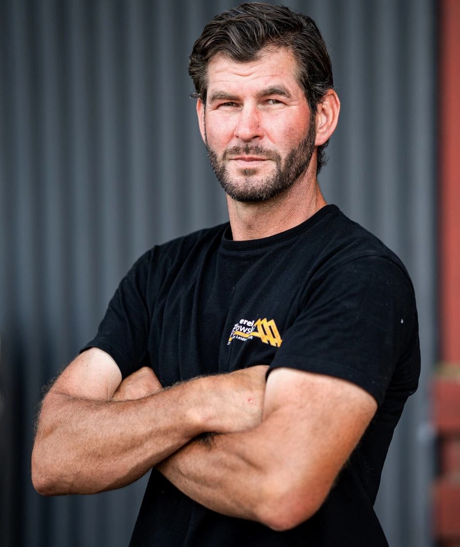 Porträt von Nando Tulke, einem erfahrenen Handwerker, der mit verschränkten Armen in die Kamera blickt.