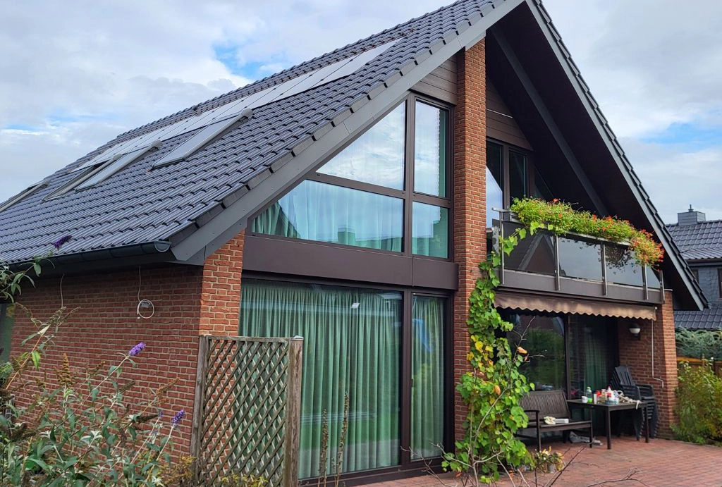 Modernes Einfamilienhaus mit dunklem Ziegeldach, Solarpaneelen und Klinkerfassade, ein Referenzprojekt der Zimmerei Pawlowski GmbH.