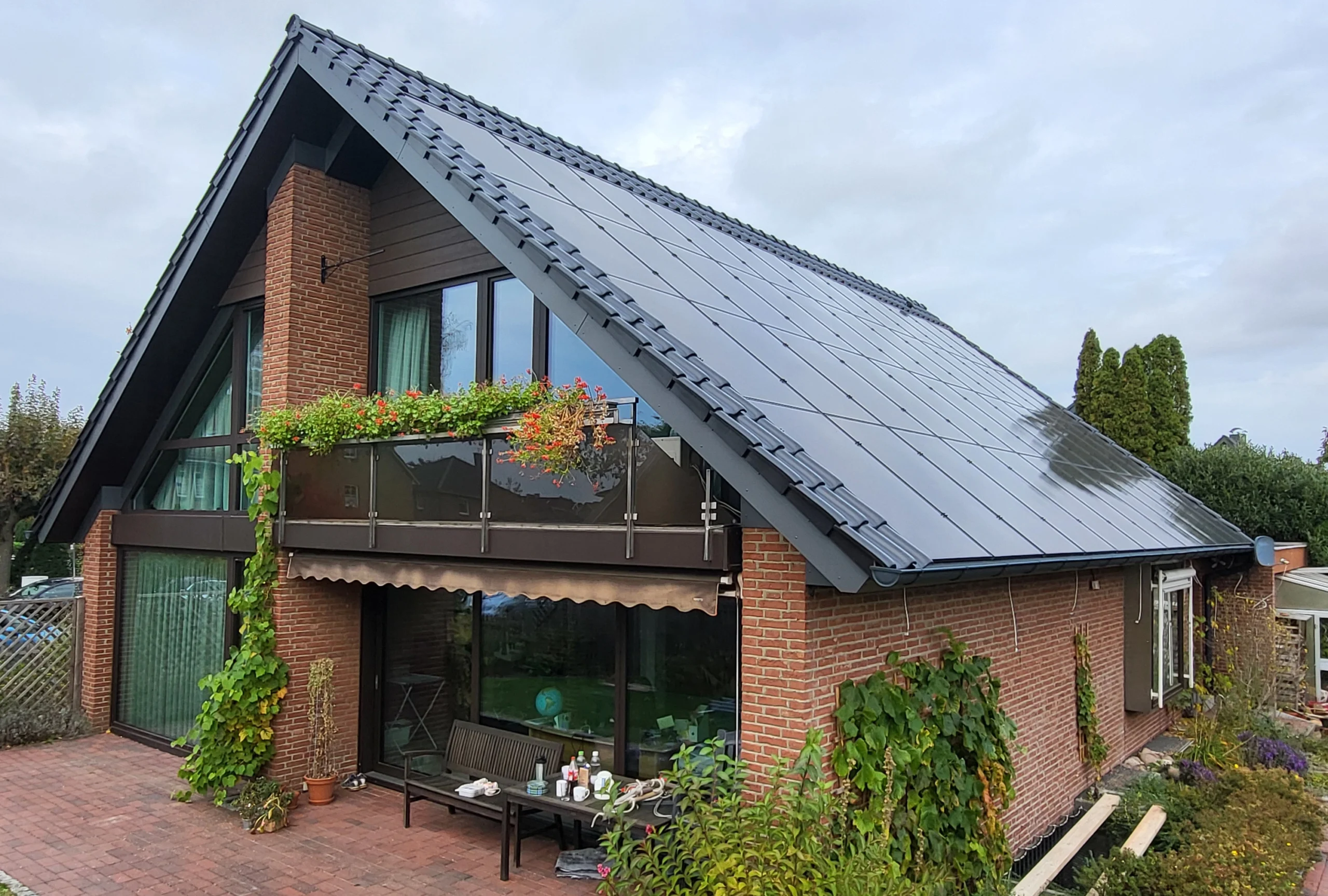 Dachsanierung eines modernen Einfamilienhauses mit dunklem Ziegeldach und effizienten Photovoltaik-Modulen, ausgeführt von einem erfahrenen Zimmereibetrieb.