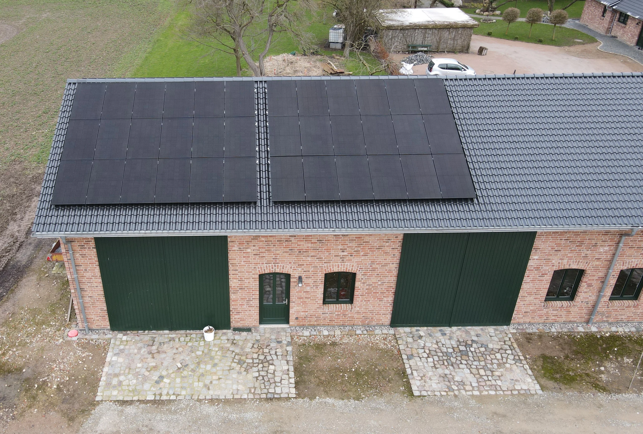 Zimmerei Pawlowski GmbH installierte Photovoltaikmodule auf diesem Ziegelgebäude mit neuem Dach für nachhaltige Energieerzeugung und moderne Optik.