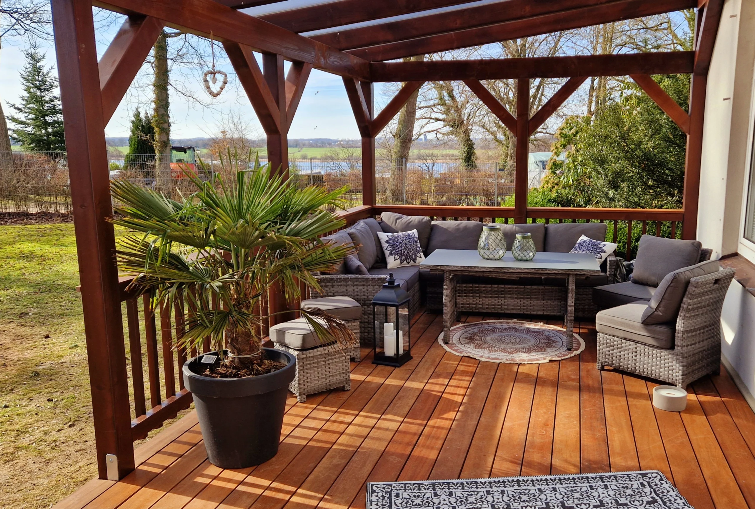 Eine stilvolle Holzterrasse mit eleganter Holzpergola, ausgestattet mit modernen Loungemöbeln und einer schönen Aussicht ins Grüne.