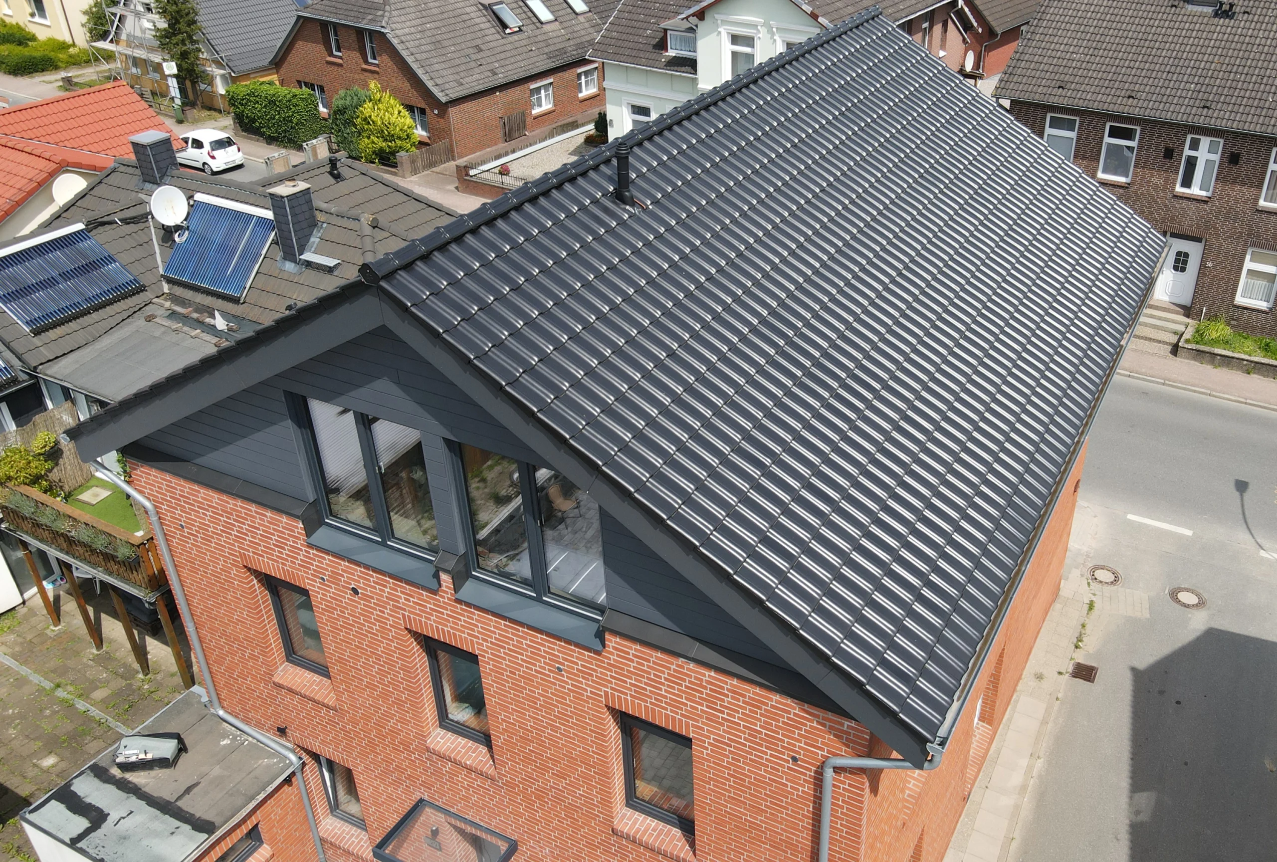 Modernes Wohnhaus mit neu gedecktem, dunkelgrauem Ziegeldach und großer Gaube, ein Beispiel für hochwertige Dacharbeiten und Gaubenbau.