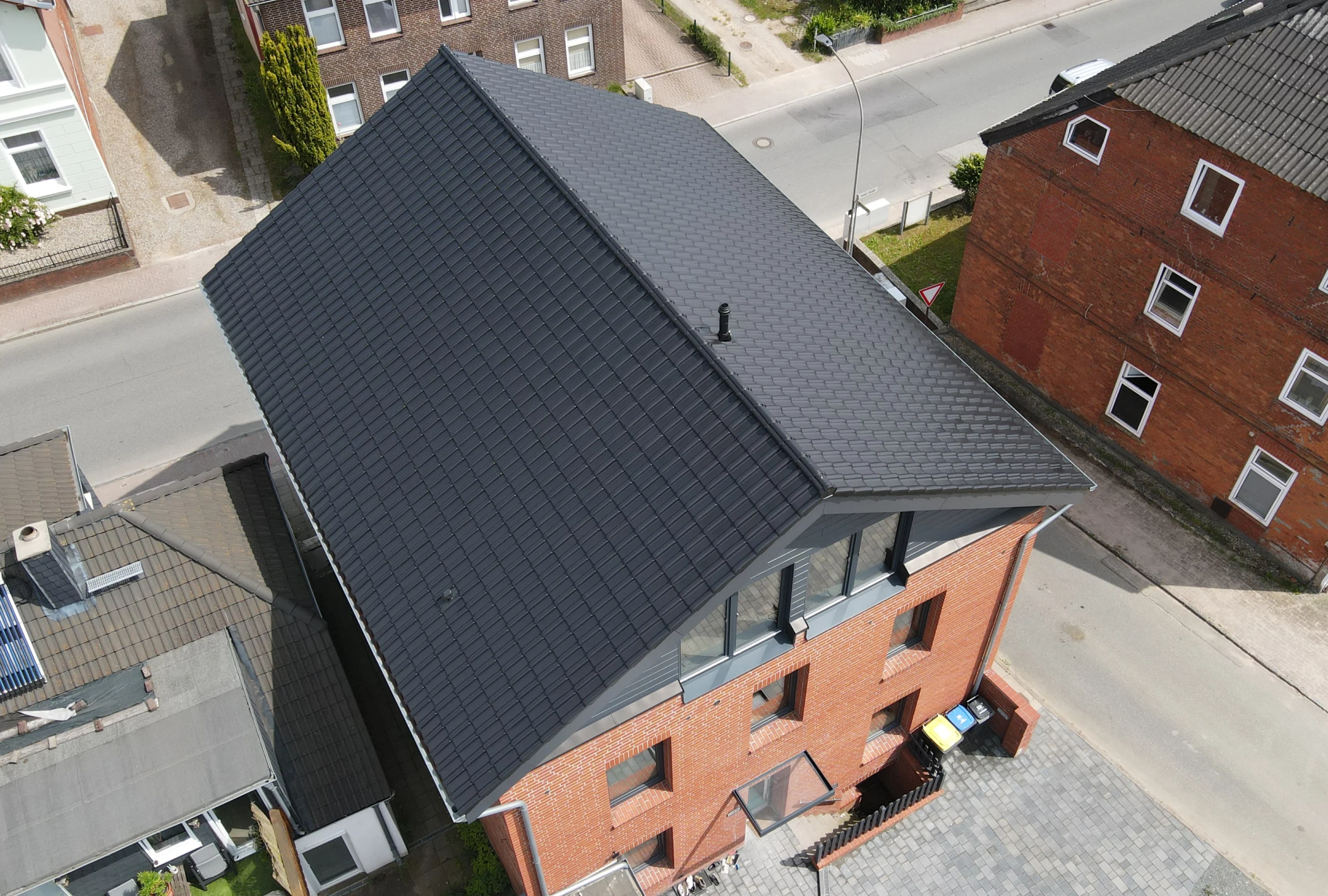 Luftaufnahme eines modernisierten Hauses mit neuem, dunkelgrauem Ziegeldach, das von Zimmerei Pawlowski GmbH professionell gedeckt wurde.
