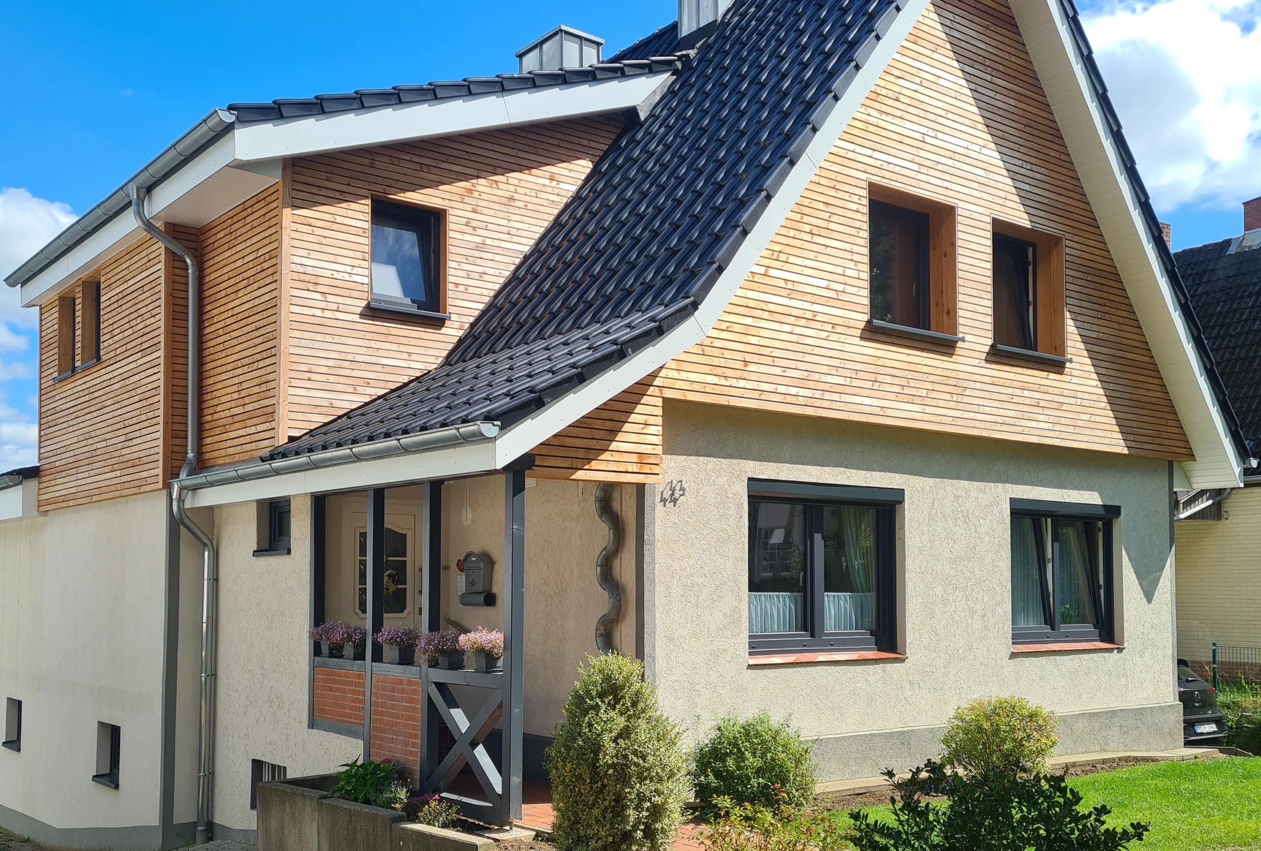 Modernes Wohnhaus mit eleganter Holzfassade und neu gedecktem Dach, ein Beispiel für hochwertige Zimmererarbeiten.