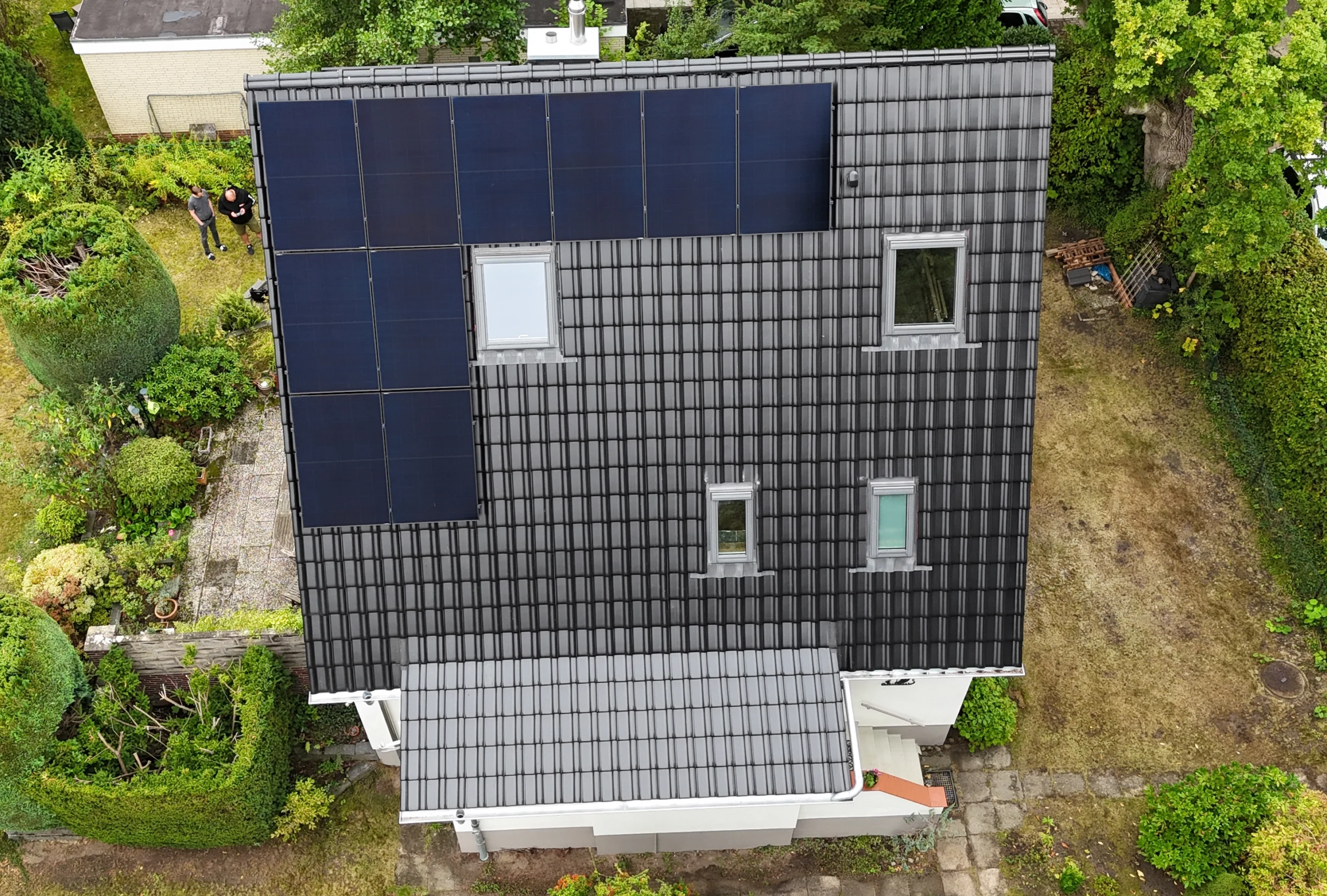 Luftaufnahme eines Hauses mit neu gedecktem Dach, integrierter Solaranlage und modernen Dachfenstern, ein Referenzprojekt für nachhaltiges Bauen.
