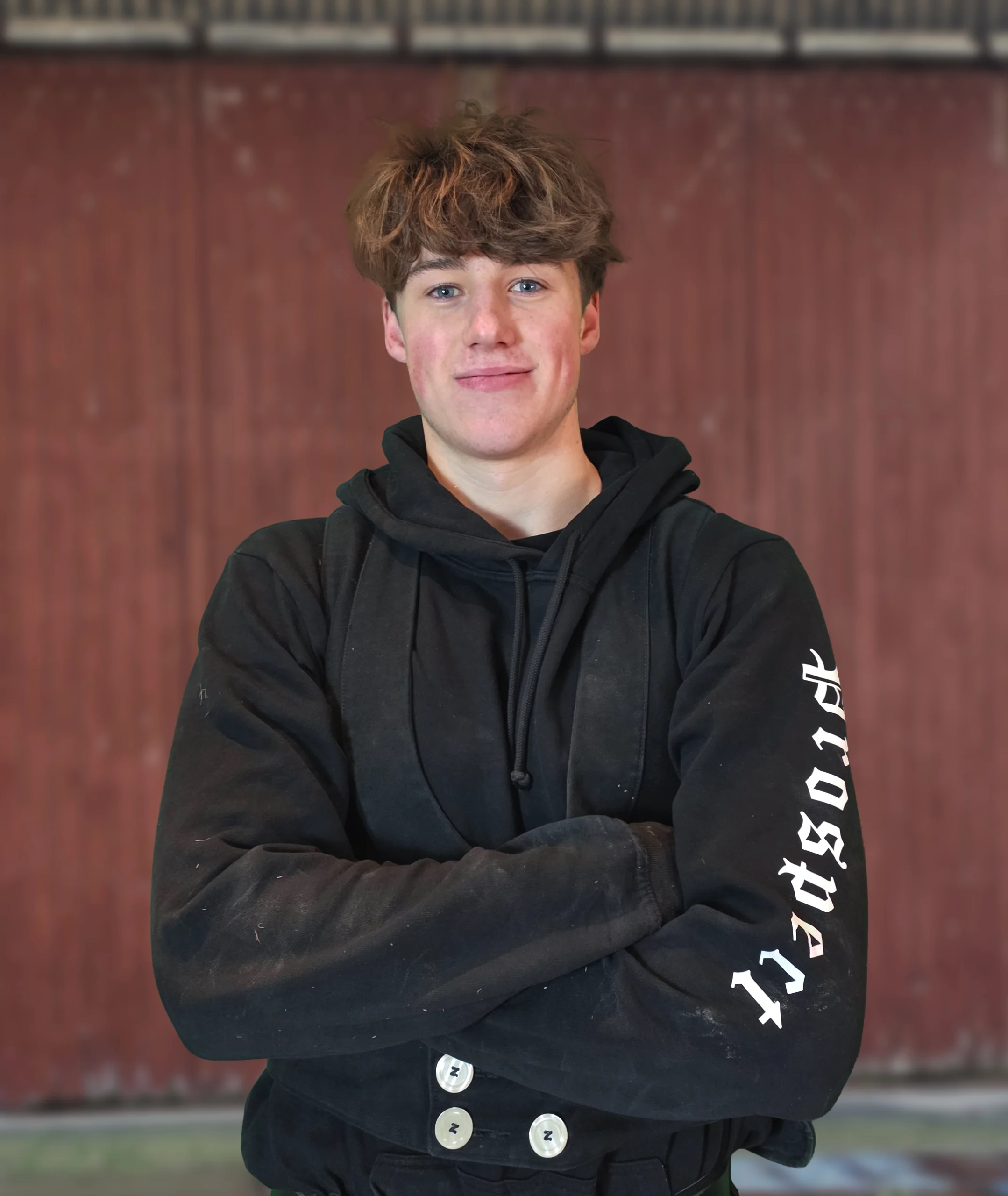 Timo Mercier, ein junger Zimmerer der Zimmerei Pawlowski, lächelt in traditioneller Zunftkleidung mit verschränkten Armen.